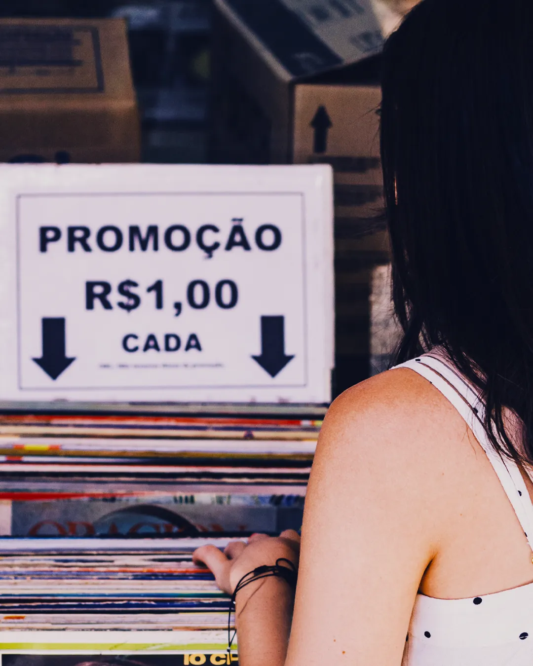 Consumidora diante de uma placa de promoção de R$ 1,00